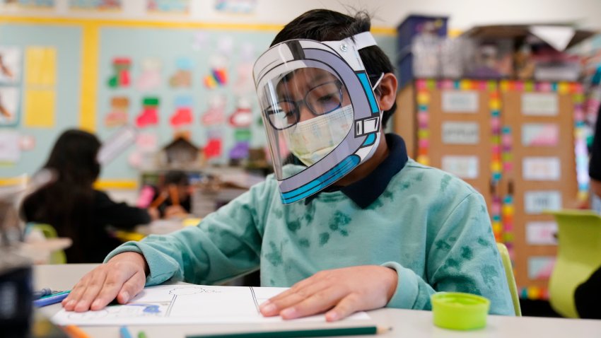 FILE – A student wears a mask and face shield in a 4th grade class amid the COVID-19 pandemic at Washington Elementary School on Jan. 12, 2022, in Lynwood, Calif. Four years after the COVID-19 pandemic closed schools and upended child care, the CDC says parents can start treating the virus like other respiratory illnesses.